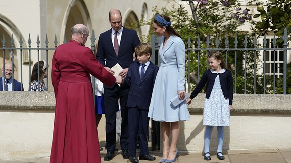 Prinzessin Charlotte (r-l), Kate, Herzogin von Cambridge, Prinz George, Prinz William, Herzog von Cambridge, schütteln David Conner, Dekan von Windsor, nach der Ostermesse in der St. George's Chapel auf Schloss Windsor die Hand.