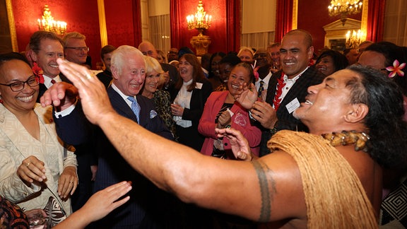 König Charles III. bekommt vom ehemalige samoanischen Rugbyspieler Freddie Tuilagi Tanzbewegungen gezeigt.