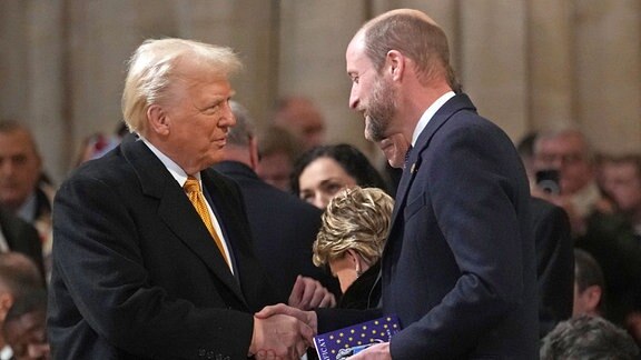 Donald Trump schüttelt Prinz William in der Kathedrale Notre Dame die Hand.