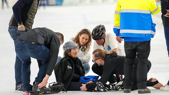 Menschen knien und sitzen auf dem Eis.