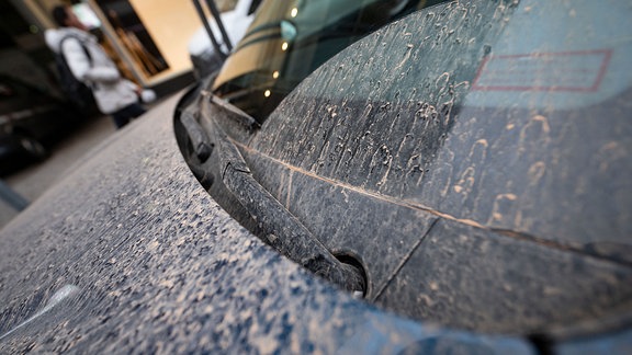 Ein Auto ist von rötlichem Staub bedeckt