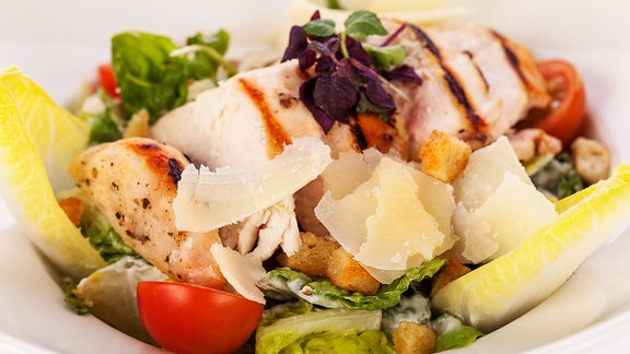 Frischer, leckerer Caesarsalat mit gegrillter Hähnchenbust, Parmesansplittern und Croutons.