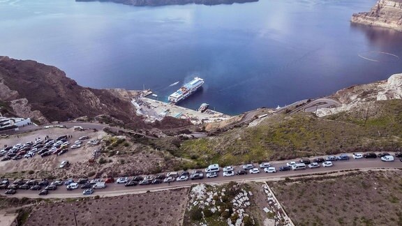Menschen stehen mit ihren Autos Schlange vor dem Hafen von Athinios, um Santorini aufgrund der verstärkten seismischen Aktivität der letzten Tage zu verlassen