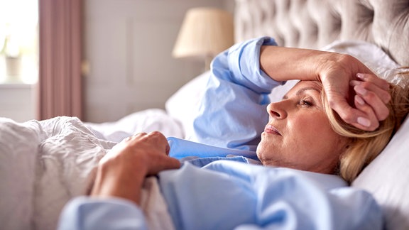Eine Frau liegt wach in einem Bett