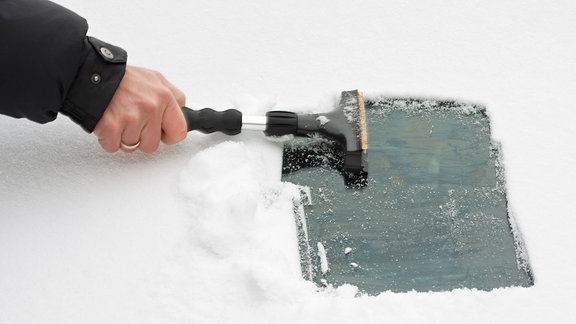 Schnee wird von einer Windschutzscheibe gefegt