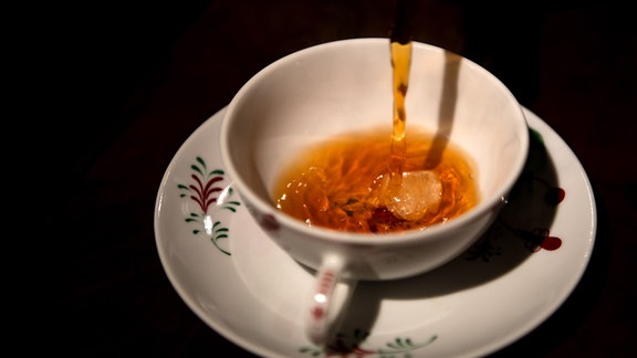 Schwarzer Tee wird in eine Tasse gegossen.