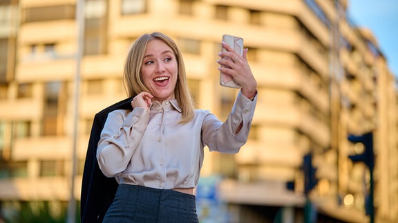 Eine Frau posiert vor ihrem Handy.
