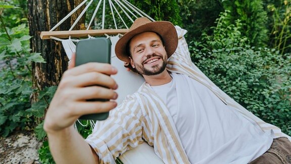 Ein Fotografiert sich selbst mit seinem Handy.