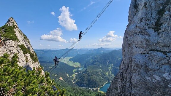 Bergsteiger klettern die „Himmelsleiter“ am Donnerkogel im Dachsteingebirge im Salzkammergut hinauf