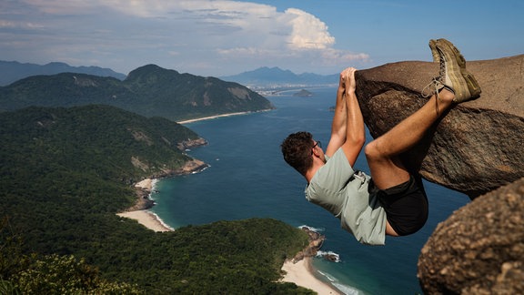 Ein Mann hängt an dem «Pedra do Telegrafo» mit dem Meer im Hintergrund.