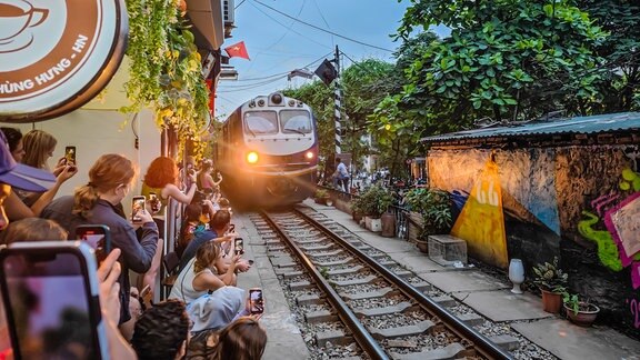 Zug fährt in Hanois Train Street an Menschen vorbei.