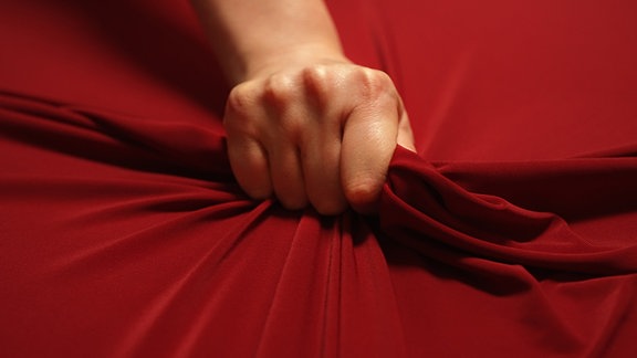 Eine Hand greift in ein Bettlaken (Inszenierung)
