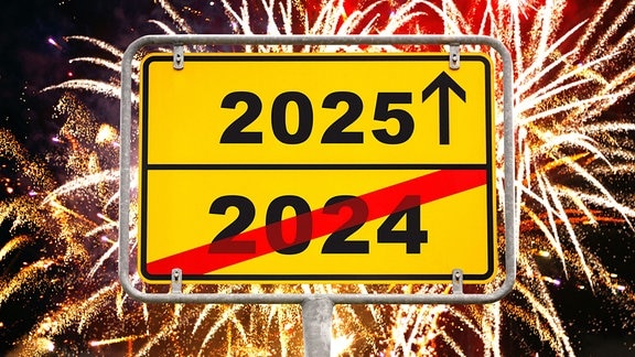 Die Jahreszahlen von 2024 (durchgestrichen) und 2025 stehen auf einem Ortsausgangssschild vor einem Feuerwerkshimmel