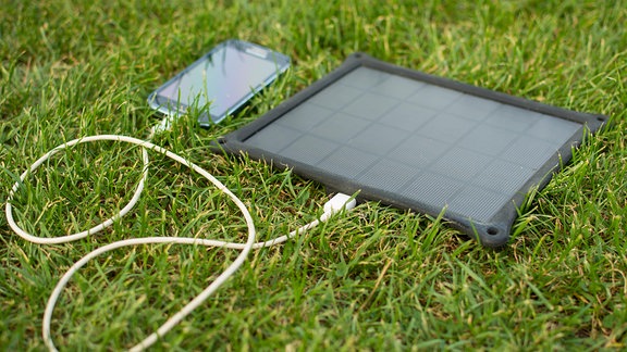 Ein Smartphone an einem mobilen Solarladegerät