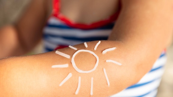 eine Sonne mit Sonnenschutzlotion auf einen Kinderarm gezeichnet