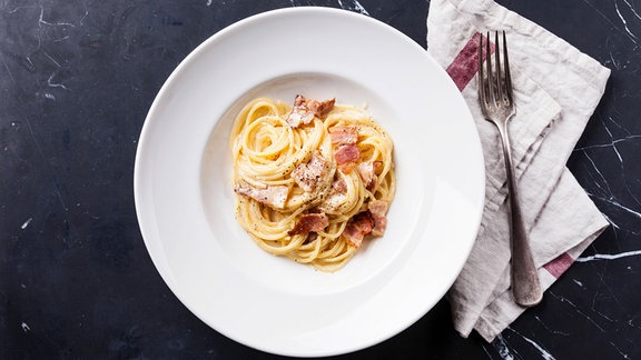 Pasta Carbonara auf weißem Teller mit Parmesan