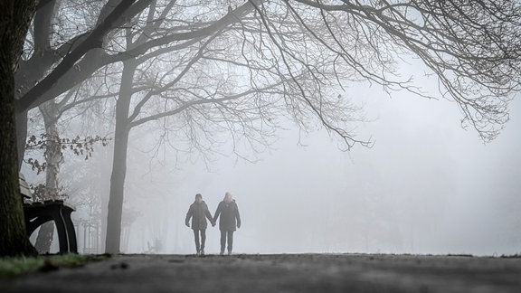 Ein Paar geht im Nebel spazieren.