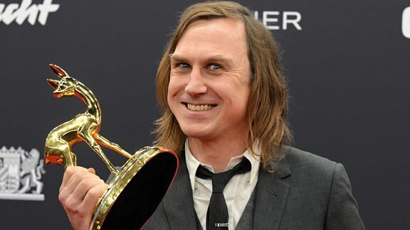 Lars Eidinger, Preisträger in der Kategorie "Schauspieler National", zeigt seinen Bambi bei der Bambi-Verleihung 2024.