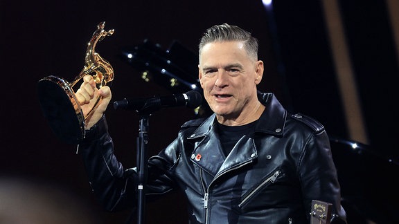 Bryan Adams, Preisträger in der Kategorie "Legende", zeigt seinen Bambi auf der Bühne bei der Bambi-Verleihung 2024.