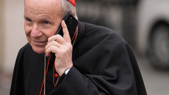 Kardinal Christoph Schonborn hält ein Handy ans Ohr.