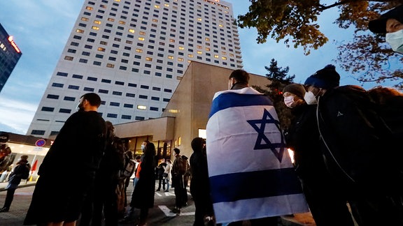 Ein Demonstrant trägt 2021 die Fahne Israels über den Schultern.