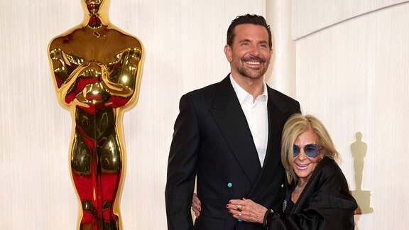 Oscar nominierter Schauspieler pausiert mit seiner Mutter vor einer großen Statue