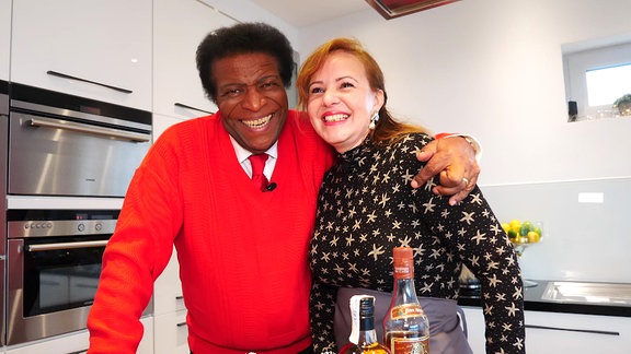 Roberto Blanco umarmt eine Frau, während beide in einer Küche stehen.