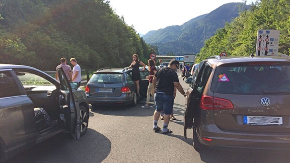 Autofahrer und Mitreisende steigen während eines Staus aus ihren PKW aus und versuchen sich einen Überblick über die Lage zu verschaffen.