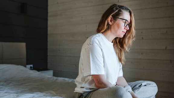 Einsame Frau sitzt zu Hause im Bett