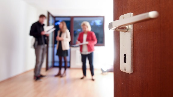 Eine Maklerin spricht mit Interessenten bei einer Wohnungsbesichtigung