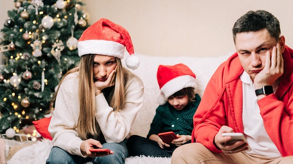 Genervte Familie an Weihnachten mit Smartphone in der Hand