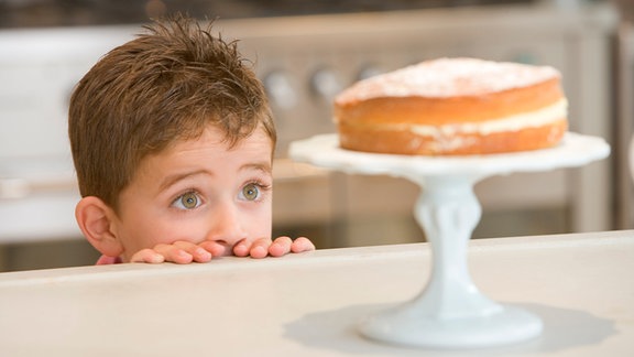 Ein Junge schaut auf einen Kuchen.