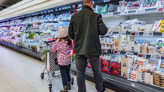 Ein Mann und ein Mädchen steht im Supermarkt vor einem Kühlregal