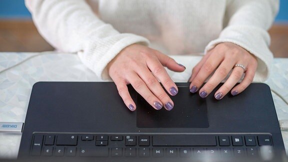 Eine Frau schreibt auf eienm Laptop.