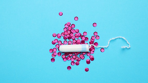 Tampon und rosa Pailletten auf hellblauem Hintergrund,