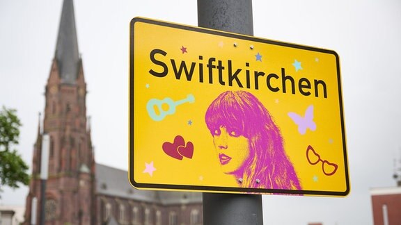 Das Ortsschild "Swiftkirchen" zu Ehren der Musikerin Taylor Swift hängt auf dem Heinrich-König-Platz, vor der Propsteikirche St. Augustinus.