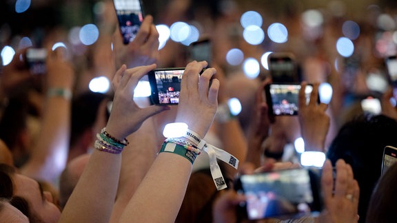 Zuschauer filmen während des Konzerts von Sängerin Taylor Swift in der Veltins-Arena mit ihren Smartphones.