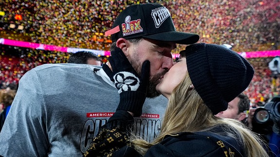 Taylor Swift und Travis Kelce küssen sich.