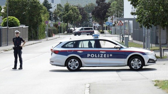 Ein Polizist und ein Polizeiwagen stehen am Einsatzort.