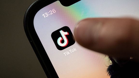 Ein Teenager tippt auf das Icon TikTok-App auf einem Smartphone.