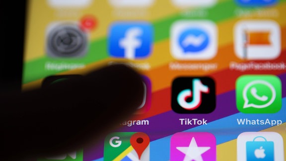 Ein Finger im Begriff, auf das Symbol der TikTok-App auf einem Smartphone zu drücken.