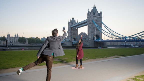 Touristen fotografieren sich vor der Tower Bridge. 