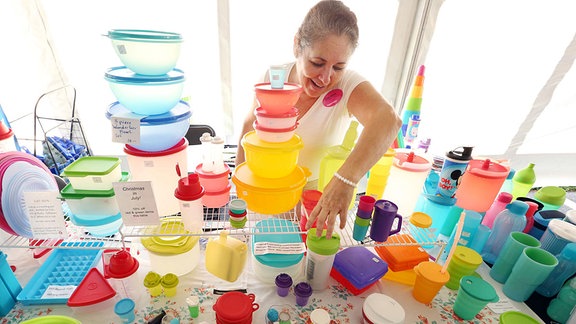 Eine Verkäuferin arrangiert eine Auswahl an Tupperware dzum Verkauf
