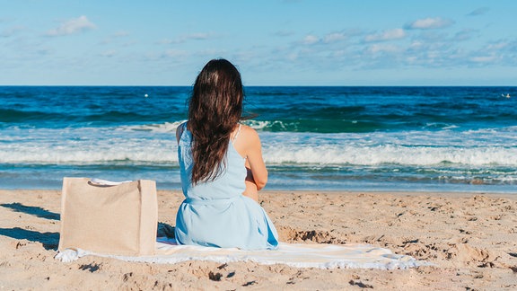 Eine Frau sitzt am Strand