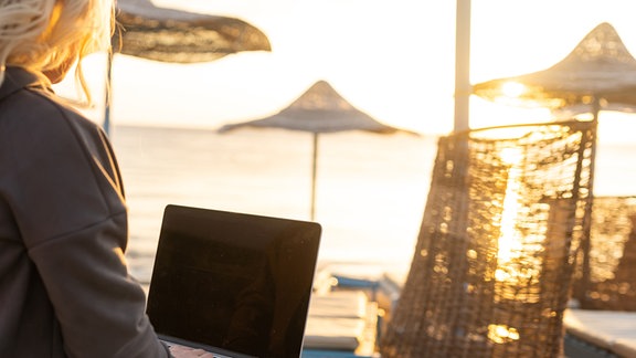 Frau mit Laptop am Strand