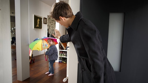 Ein junger Mann verabschiedet sich von einem Mädchen an der Haustür.
