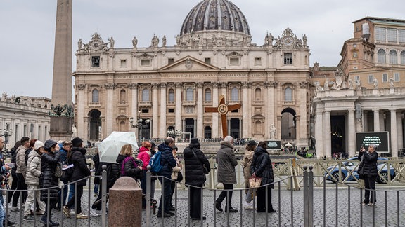Pilger kommen mit einem Kreuz vor dem Petersdom auf dem Petersplatz an, während der Papst seit 14. Februar 2025 in der Poliklinik Agostino Gemelli in Rom stationär behandelt wird.