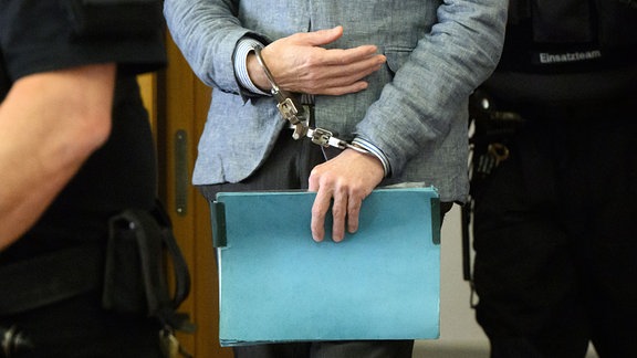 Der Angeklagte Christian B. kommt mit Handschellen in den Gerichtssaal im Landgericht Braunschweig.
