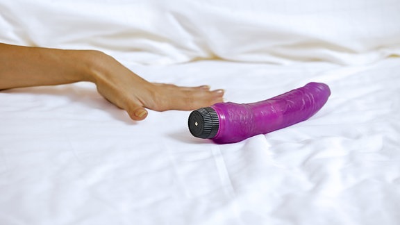 Die Hand einer Frau neben einem Vibrator