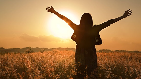 Die Silhouette einer Frau vor einem Sonnenuntergang.